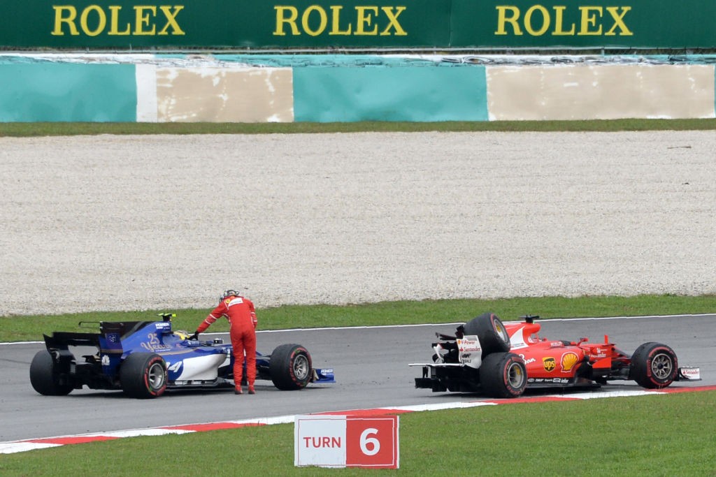 Ferrari's German driver Sebastian Vettel is given a ride by Sauber's German driver Pascal Wehrlein after he crashed past the chequered flag during the Formula One Malaysia Grand Prix in Sepang on October 1, 2017.   / AFP PHOTO / ROSLAN RAHMAN        (Photo credit should read ROSLAN RAHMAN/AFP/Getty Images)