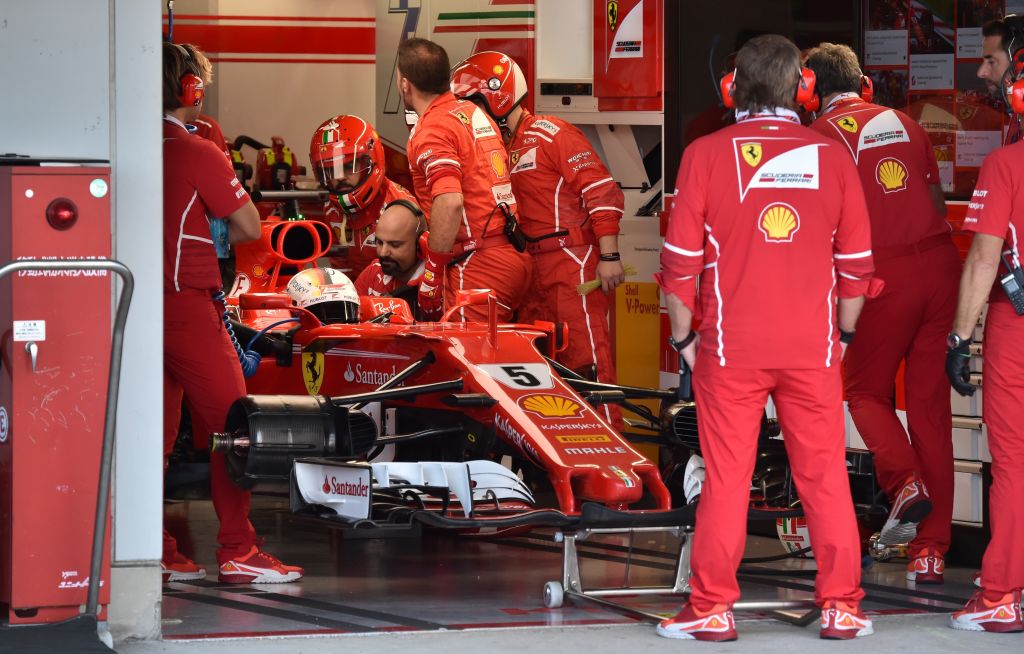 Ferrari's German driver Sebastian Vettel (L) waits for repair at the pit during the Formula One Japanese Grand Prix at Suzuka on October 8, 2017. / AFP PHOTO / POOL / KAZUHIRO NOGI (Photo credit should read KAZUHIRO NOGI/AFP/Getty Images)